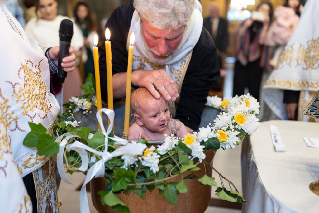 videograf botez bucuresti surprinde momentul botezului in cristelnita, cu preotul turnand apa si reactia copilului in prim-plan